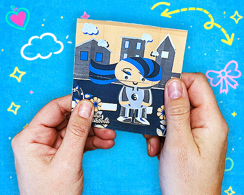 Hands holding an illustrated never-ending card featuring colorful characters and playful scenes.