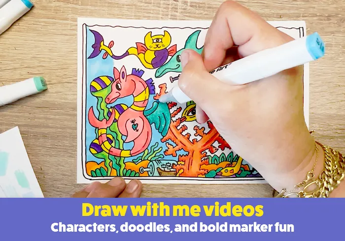 Hand drawing colorful cartoon characters with markers on paper at a desk.